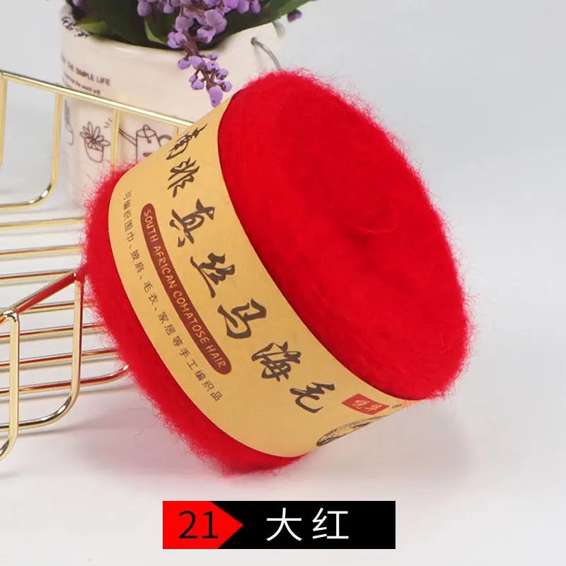 A bright red ball of silk mohair blended yarn for knitting shawls and sweaters is displayed next to a gold wire rack.