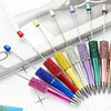 A collection of thirteen colorful beaded ballpoint pens arranged diagonally on a white surface.