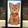 An oil painting of a puppy dog head in warm orange and brown tones framed in black.