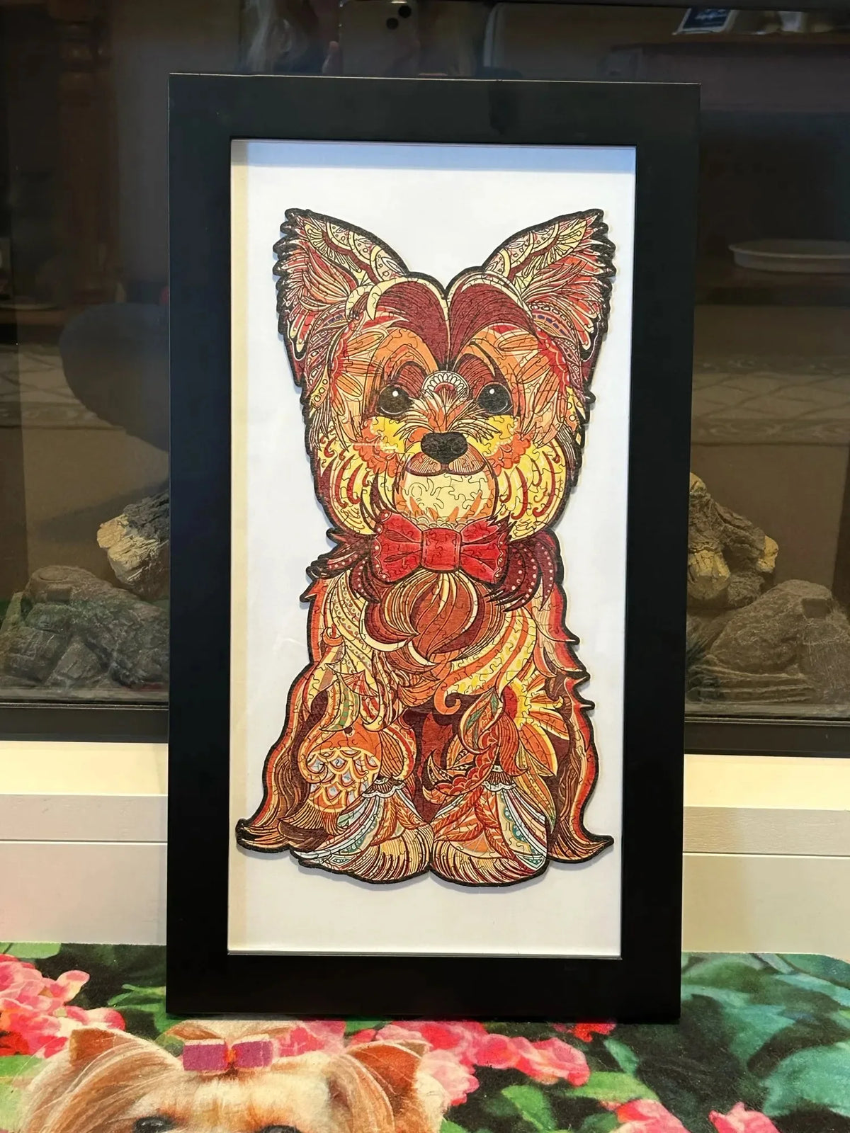 An oil painting of a puppy dog head in warm orange and brown tones framed in black.