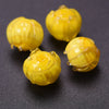 Three small yellow glass charms shaped like buds are displayed on a dark surface.