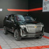 A black 1:32 diecast Cadillac Escalade pull-back model car displayed on a gray surface.