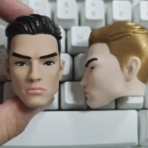 A close-up shot of a male doll's head accessory with dark hair and a golden-haired version resting on a white keyboard.