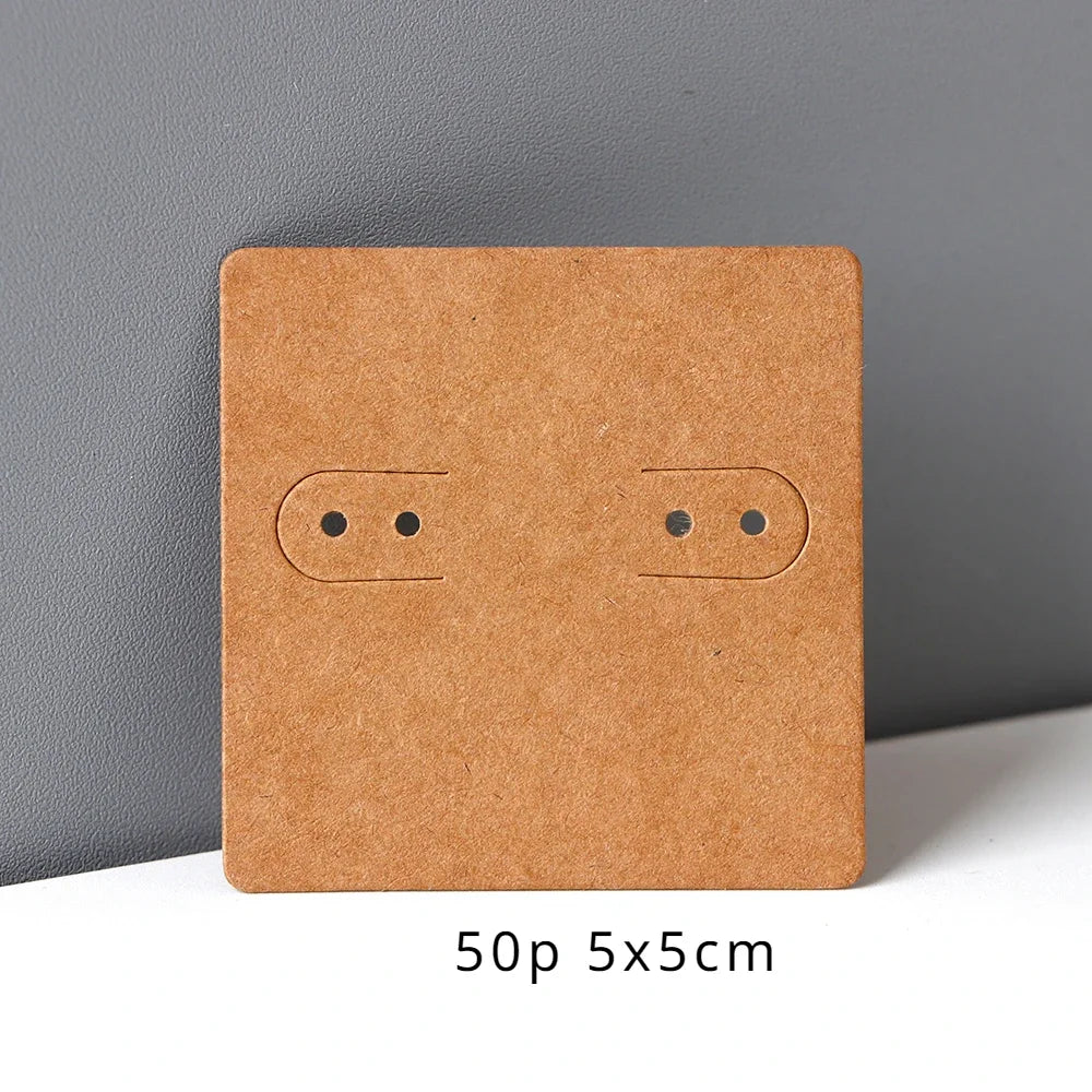 A square kraft cardboard jewelry display card with two small circular holes on the front.