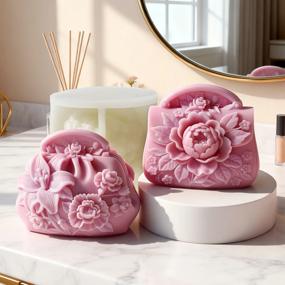 Pink silicone molds shaped like roses and flowers for candle and soap making displayed on a marble surface.