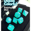 A set of seven iridescent transparent polyhedral dice in various colors displayed on a black surface.