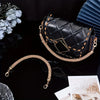 A black quilted purse with gold rhinestone straps is displayed on a dark surface.