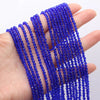 A hand holds multiple strands of small, faceted natural blue beads for DIY jewelry making.