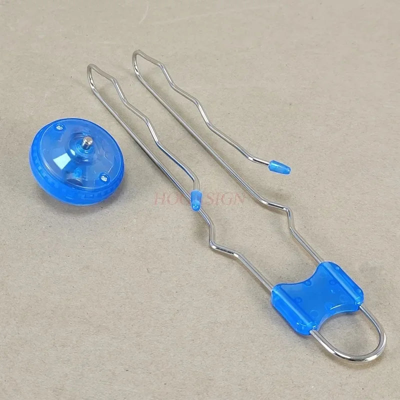 A silver magic rail twirler toy with a blue plastic base and handle resting on a brown surface.