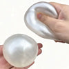 A hand is holding a smooth, translucent white squishy stress ball shaped like a spiral.