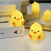 A yellow cartoon duck night light illuminating a room, displayed next to a stack of boxes.