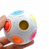 A white rainbow cube fidget toy with colorful circular cutouts and a vibrant plastic surface is held in a hand.