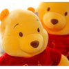 A yellow plush toy resembling Winnie the Pooh character with a brown nose and red clothing.