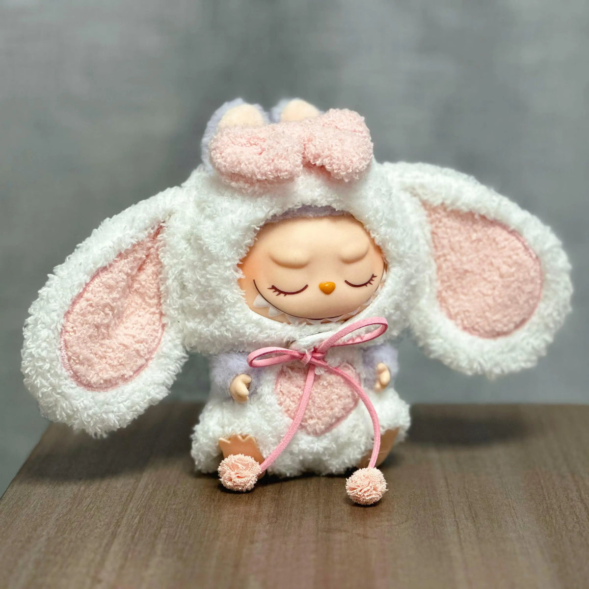 A cute, soft white rabbit costume for a doll with pink accents and long ears.