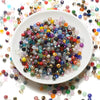 A white plate filled with multicolored faceted crystal rondelle glass beads scattered around the rim.