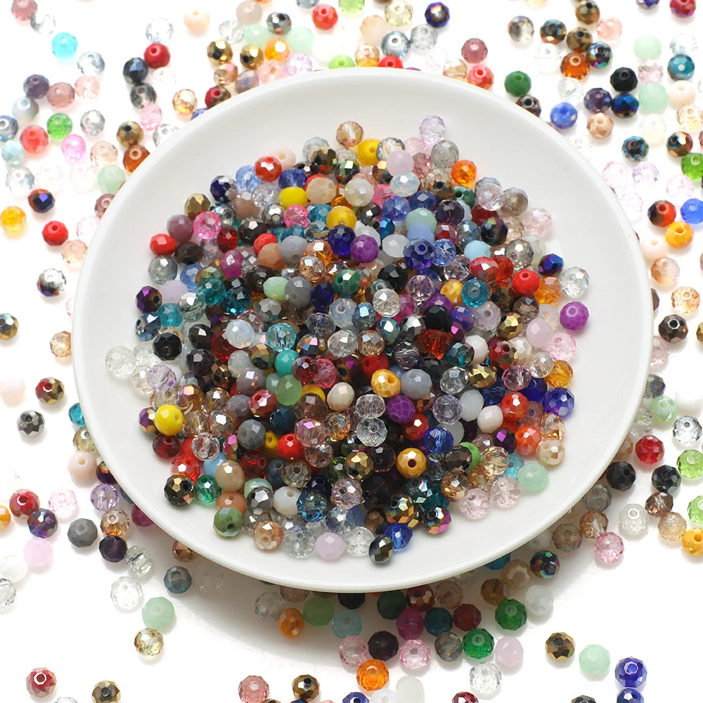 A white plate filled with multicolored faceted crystal rondelle glass beads scattered around the rim.