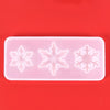 A silicone mold with three snowflake-shaped cavities for jewelry and craft projects on a red background.