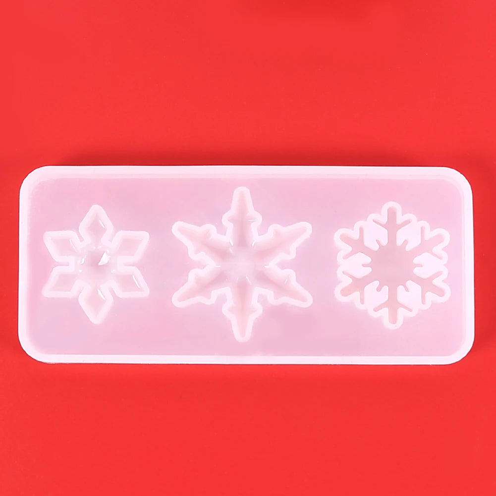 A silicone mold with three snowflake-shaped cavities for jewelry and craft projects on a red background.