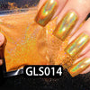 A hand displays a holographic rainbow nail glitter polish, GLS014, on a fingernail against a background of loose glitter.
