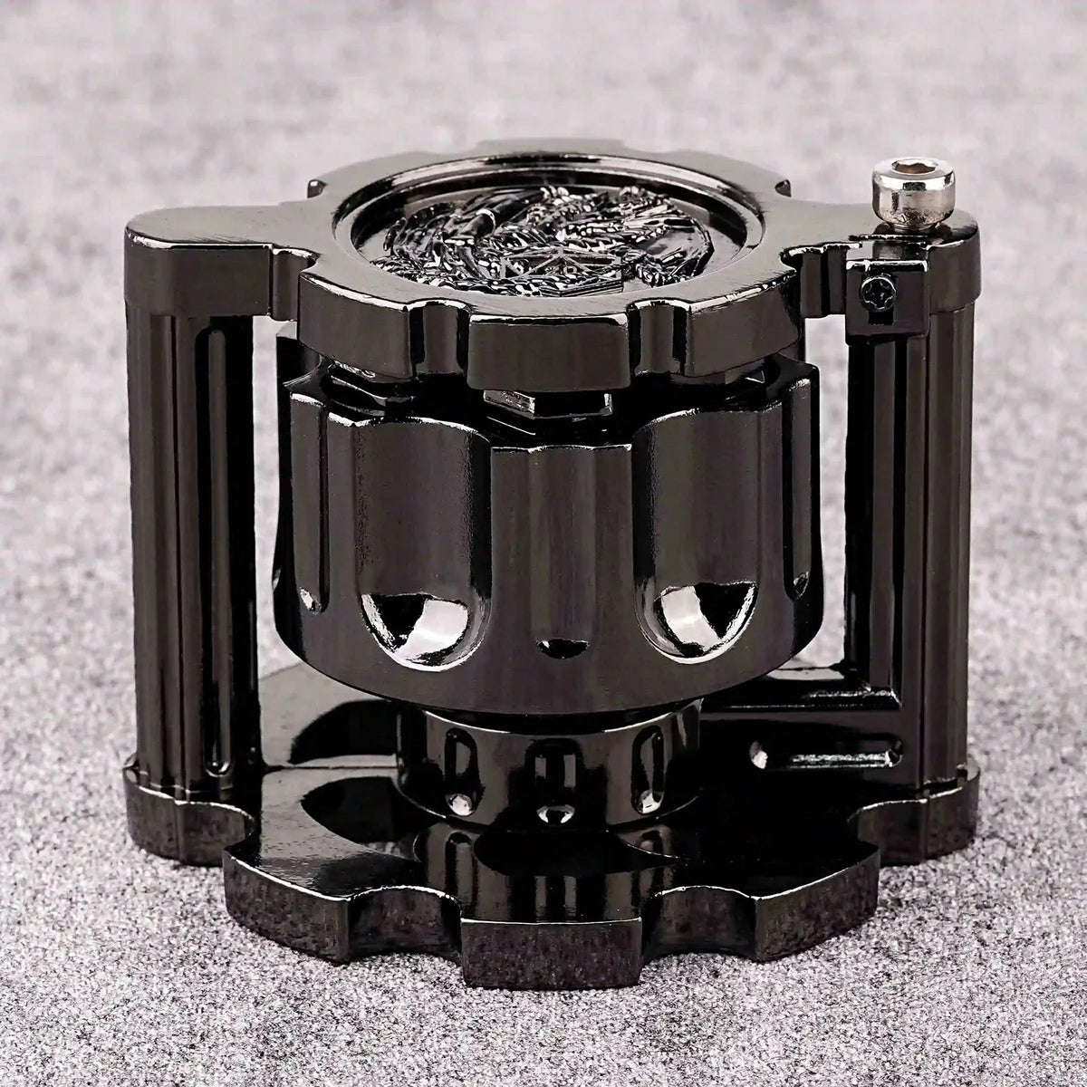 A black revolver-shaped metal dice set for RPG games resting on a gray surface.