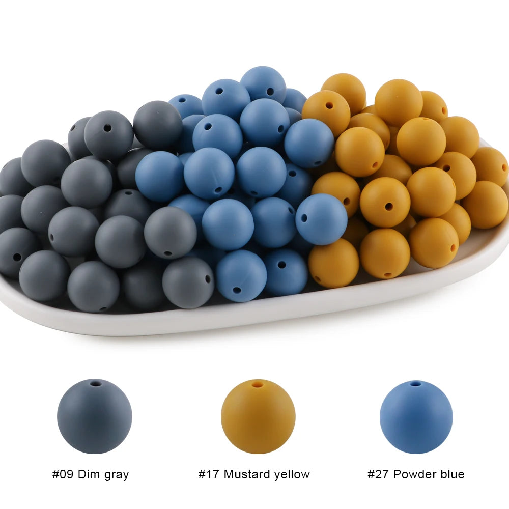 A collection of round silicone beads in various shades including dim gray, mustard yellow, and powder blue.