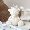 A fluffy white teddy bear sculpture with a bow, displayed on a white marble surface.