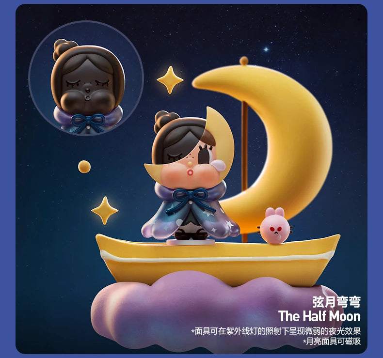 A collectible figurine of a crying character with dark hair and blue clothing is positioned in front of a large yellow cresce