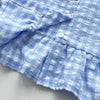 A close-up of a light blue and white checkered lace vest and wide-leg pants set.