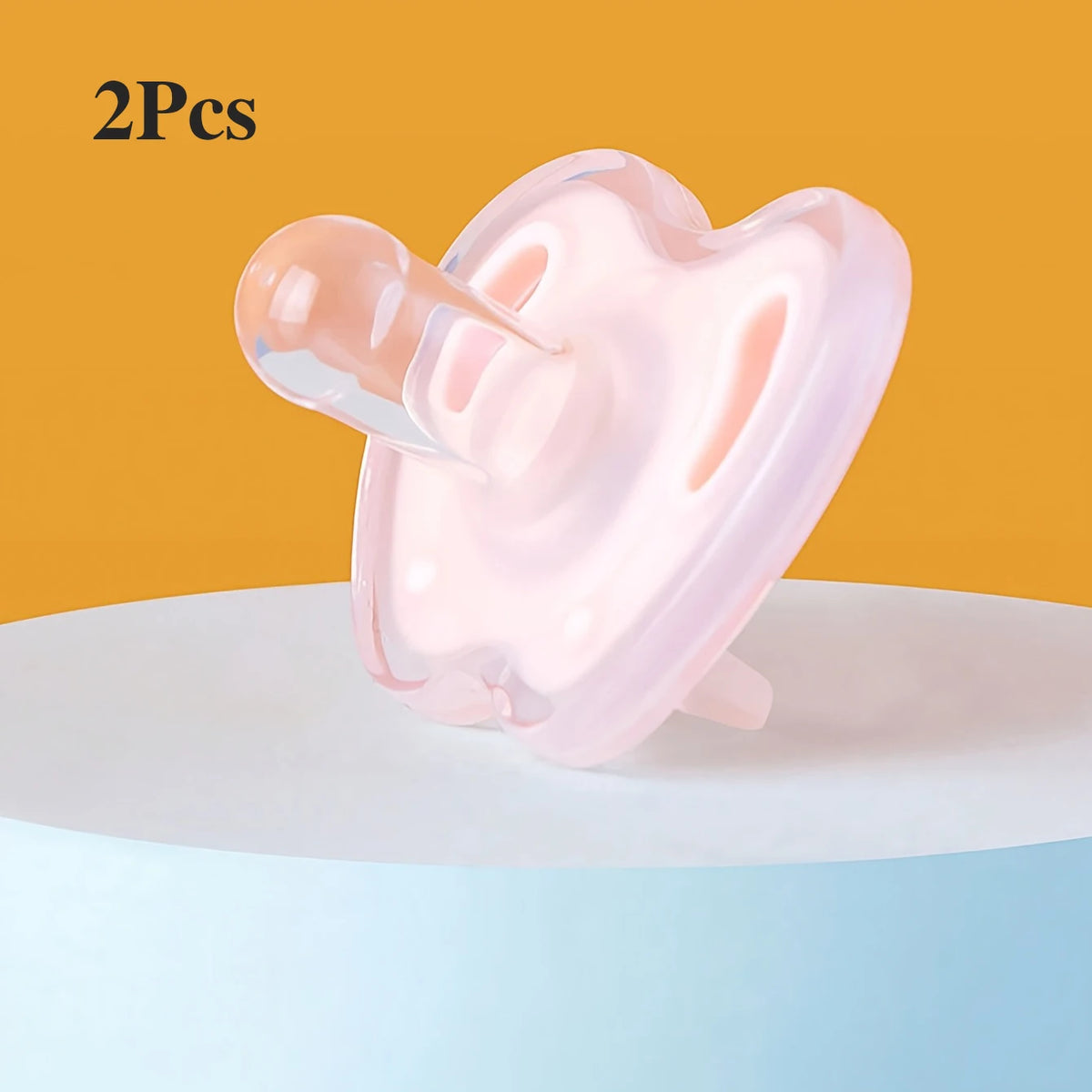 Two pink silicone baby pacifiers resting on a white surface.