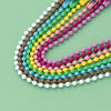 A close-up of colorful ball bead chains in a rainbow pattern, laid out on a light green surface.