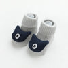 A pair of gray cotton socks with a dark blue cartoon animal face design for babies and toddlers.