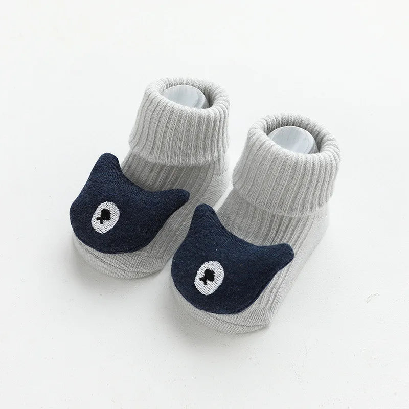 A pair of gray cotton socks with a dark blue cartoon animal face design for babies and toddlers.