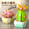 A green cactus plant arrangement made from building blocks with pink flowers and yellow accents.
