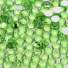 Green glass crystal flatback rhinestones for nail art and crafts scattered on a white surface
