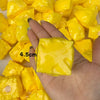 A hand holds a bright yellow crunchy cheese stress ball fidget toy with a black line marking its size.