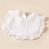 A set of eight white cotton ruffle baby bibs laid flat on a light beige background.