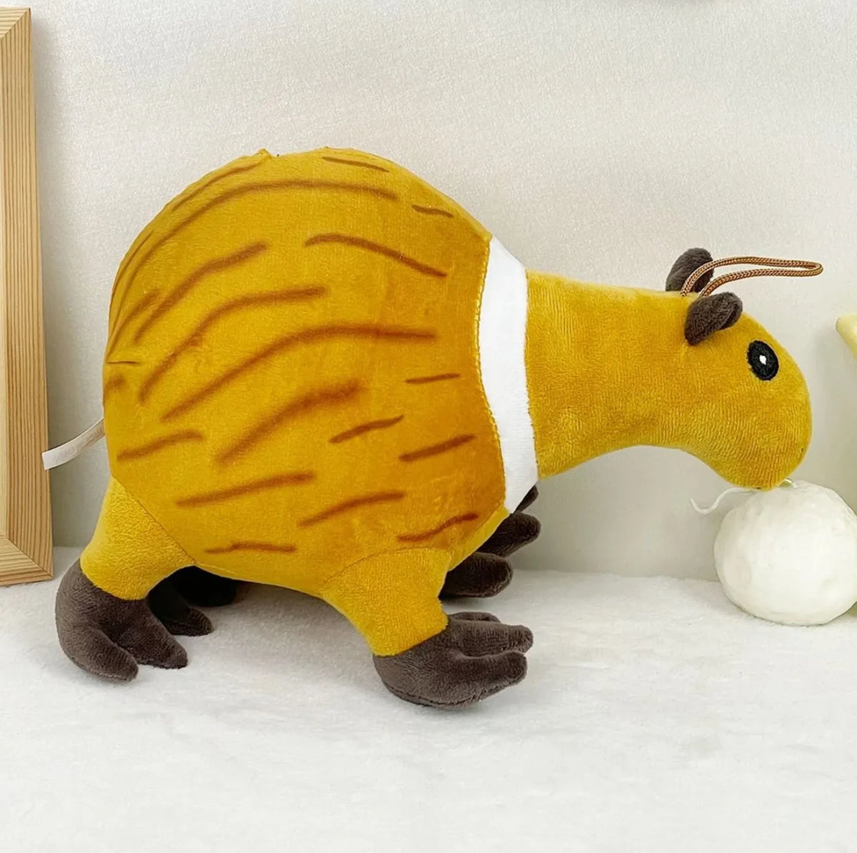 A yellow and brown shark plush toy with white markings is shown against a light background.