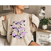 A beige sweatshirt featuring a graphic design of purple and black bats.