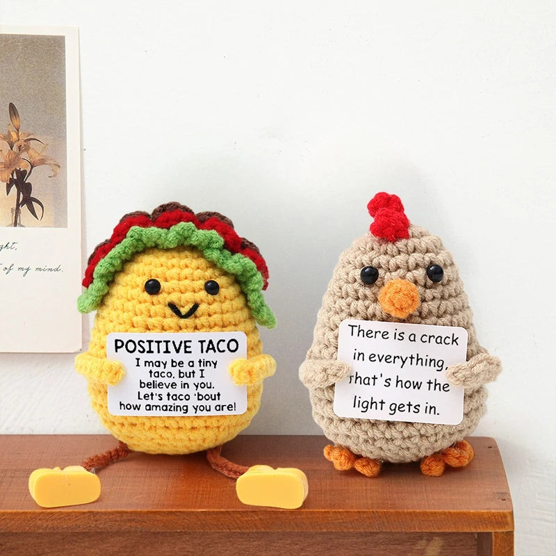 A handmade crochet owl doll with a colorful wreath and inspirational text on its chest.