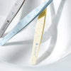 Three precision stainless steel tweezers in light blue, pale yellow, and silver are angled across a white surface.