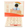 A wooden letter pencil carrier board with an illustration of a child tracing letters and a rainbow.
