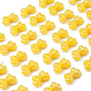A close-up of small, yellow acrylic bow beads scattered across a white background.
