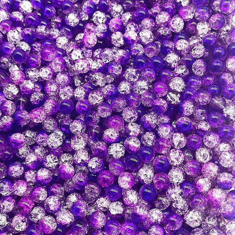 A close-up view of round glass crackle beads in various shades of purple and iridescent white.