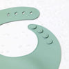 A close-up of a soft silicone waterproof baby bib in sage green with adjustable neck features.