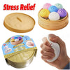 A yellow dumpling squishy stress ball is shown in a wooden basket and being held by a hand.