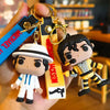 A silicone keychain featuring a figure of Michael Jackson wearing a white hat and striped outfit, attached to a metal clip.