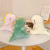 Three soft plush dinosaur toys in pink, green, and white are displayed on a white table.