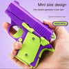 A hand holds a purple and lime green mini pistol toy designed for one-handed gameplay.
