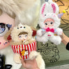A hand holds a Nommi Childhood Series blind box collectible doll with pink and white fur and a pink and white rabbit plush to