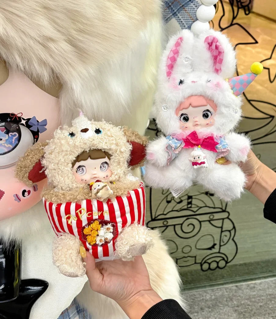 A hand holds a Nommi Childhood Series blind box collectible doll with pink and white fur and a pink and white rabbit plush to